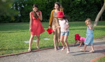 A joyous family experience in a lush Portugal park, featuring playful activities between young girls and adults.