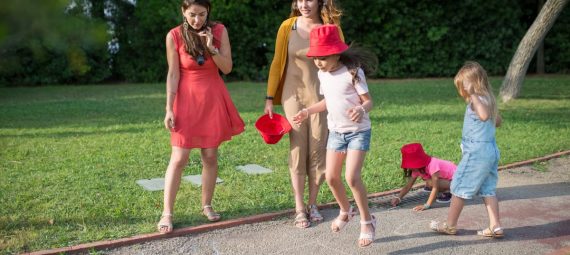 A joyous family experience in a lush Portugal park, featuring playful activities between young girls and adults.